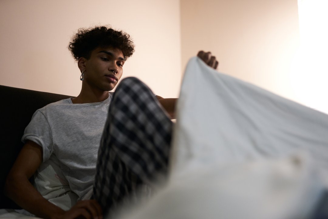 young man getting into bed to sleep