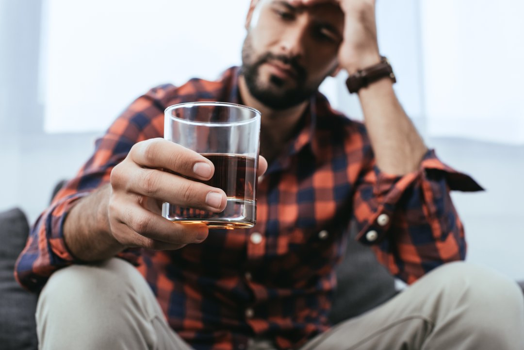 young man contemplating a glass of whiskey