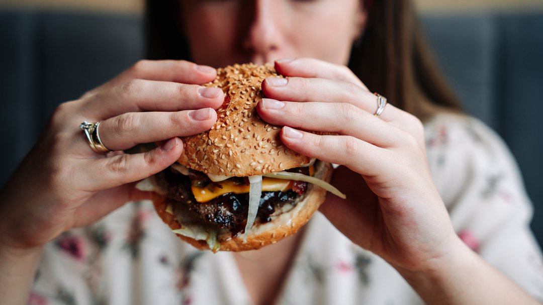 woman indulging in a juicy burger