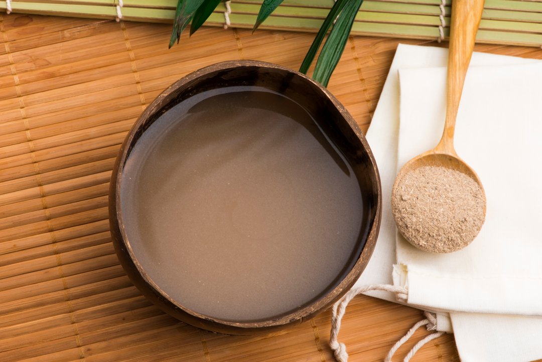 bowl of kava liquid and a scoop of kava powder