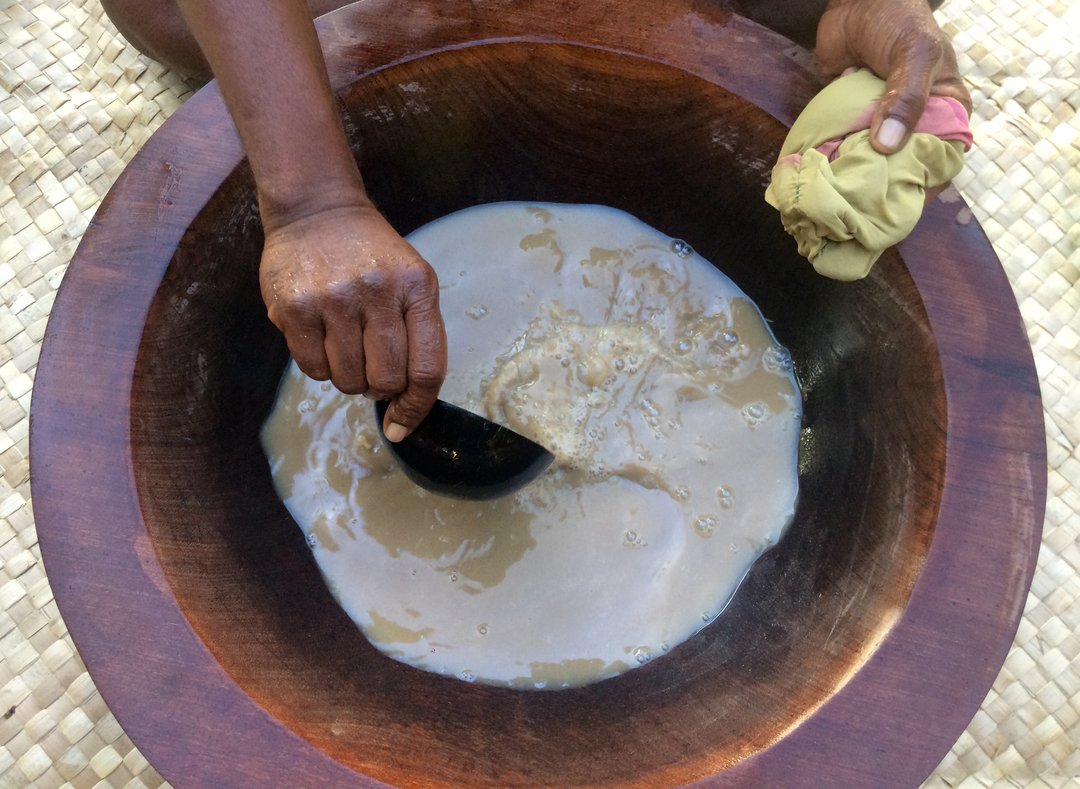 pacific islander scooping traditional kava drink from a basin