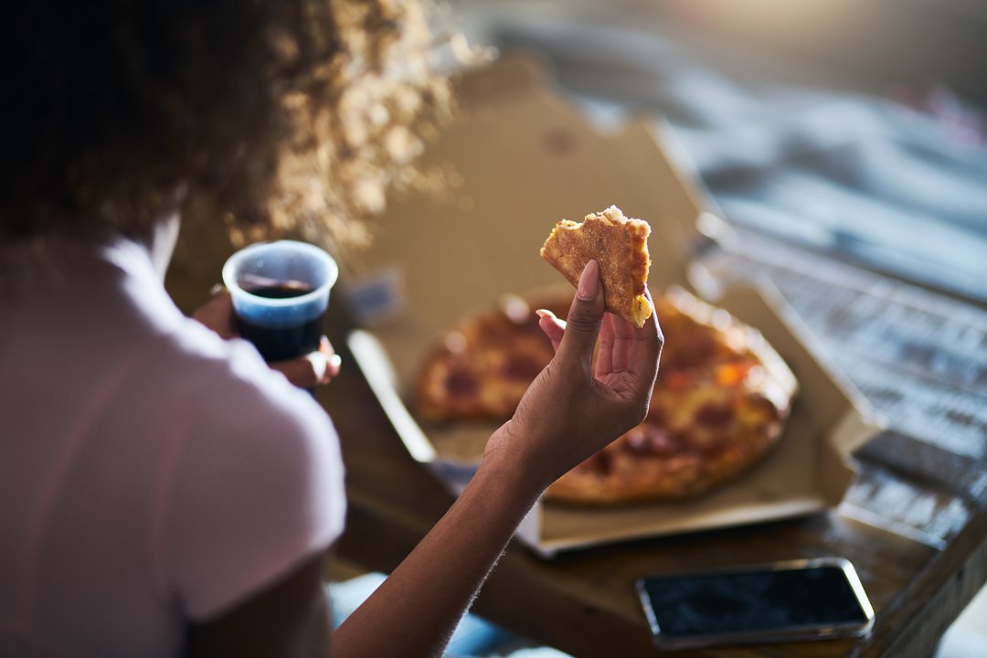 woman enjoying a slice of pizza and coke