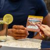 two hands exchanging a gummy bag while a drink is sitting on the table