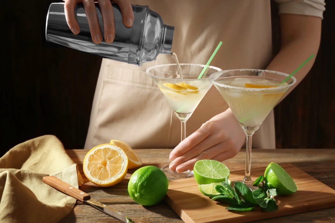 Woman making cocktail with tequila at table