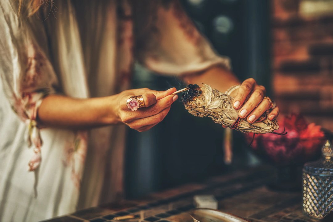 Shaman woman's hand lighting a blunt of herbs for meditative ritual