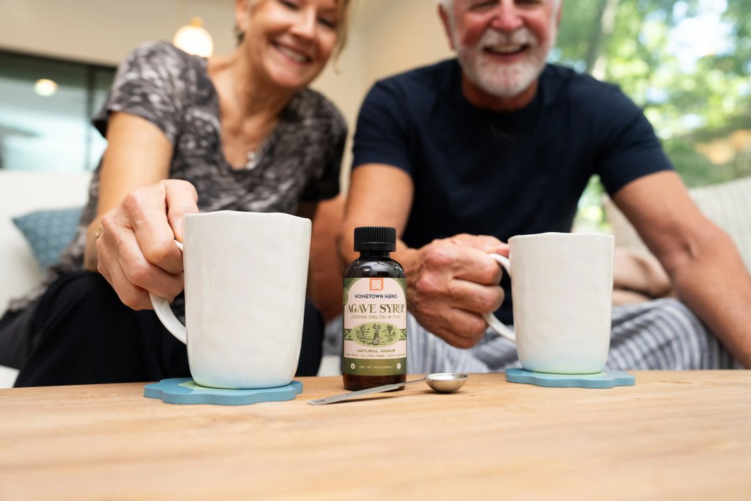 two older adults drinking from mugs filled with coffee and thc-infused syrup