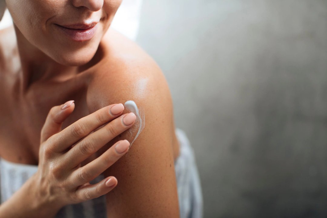 woman applying lotion as part of her skin care routine