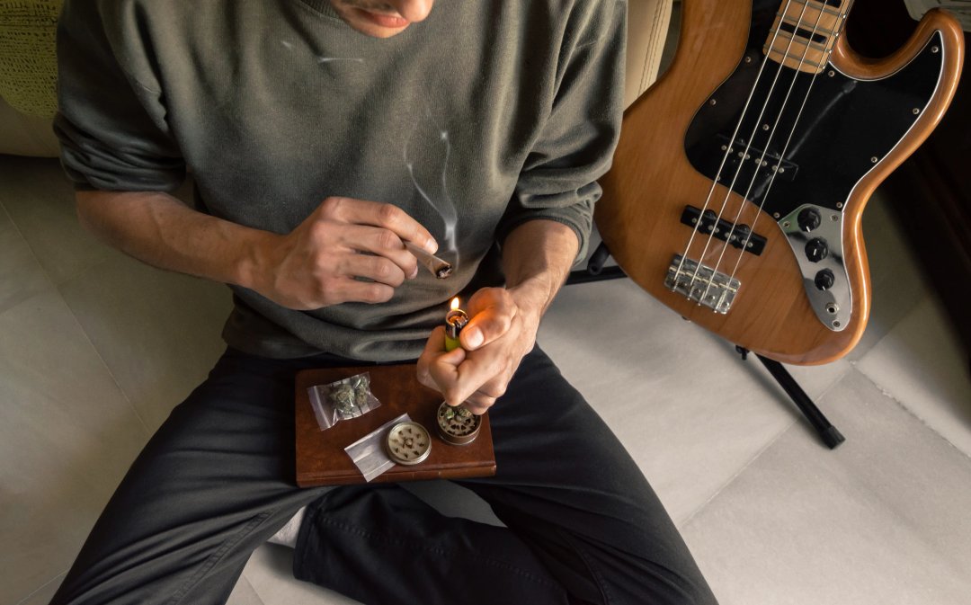 musician smoking some cannabis bud while preparing to play his guitar