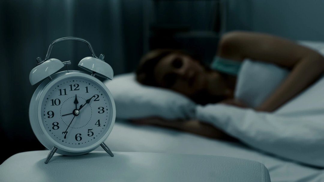 clock next to woman at bedtime