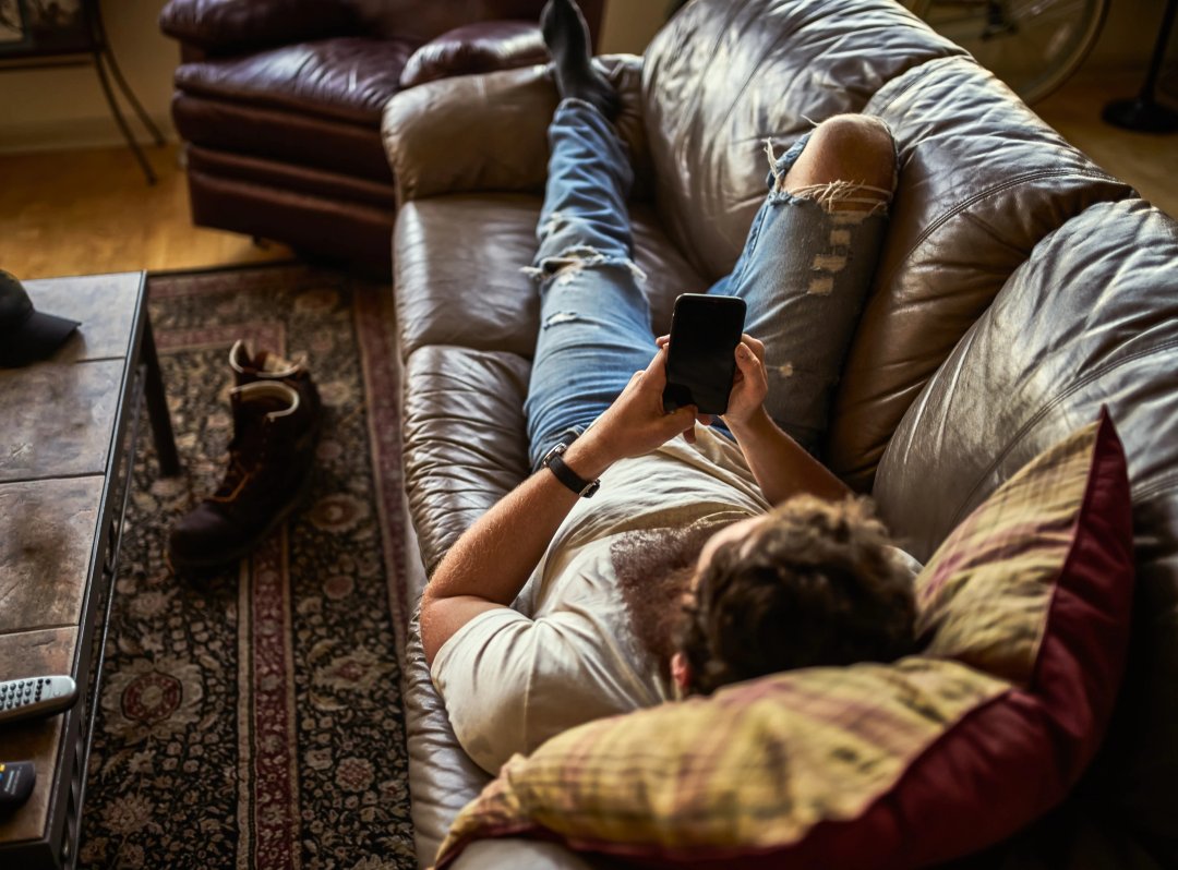 Man relaxing on his couch with a phone