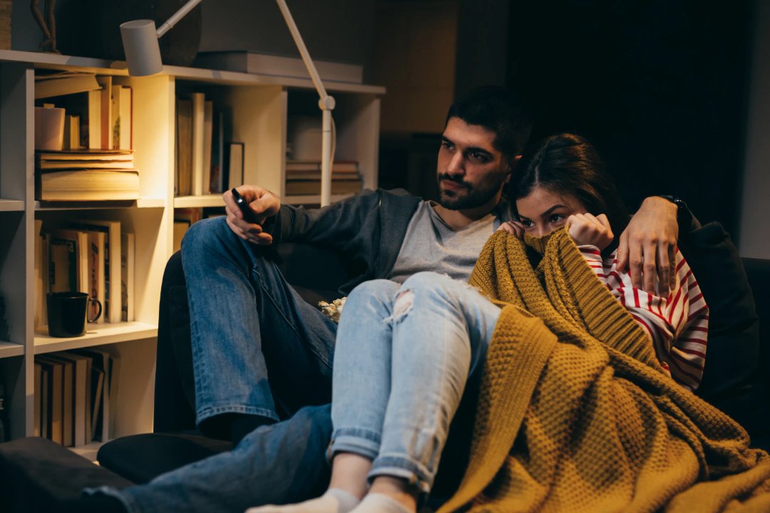 couple cuddling as they watch a spooky movie together