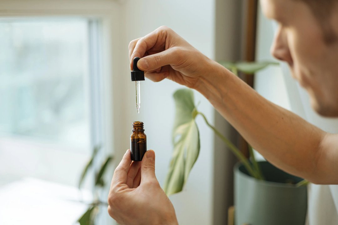 man holding the dropper of a cannabis tincture