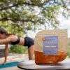 Woman doing yoga in the back with a bag of Mango Gummies in the front