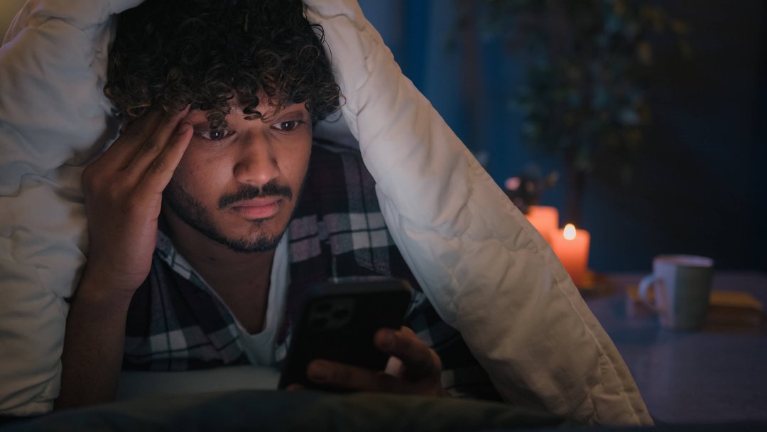 man reading on his phone in bed