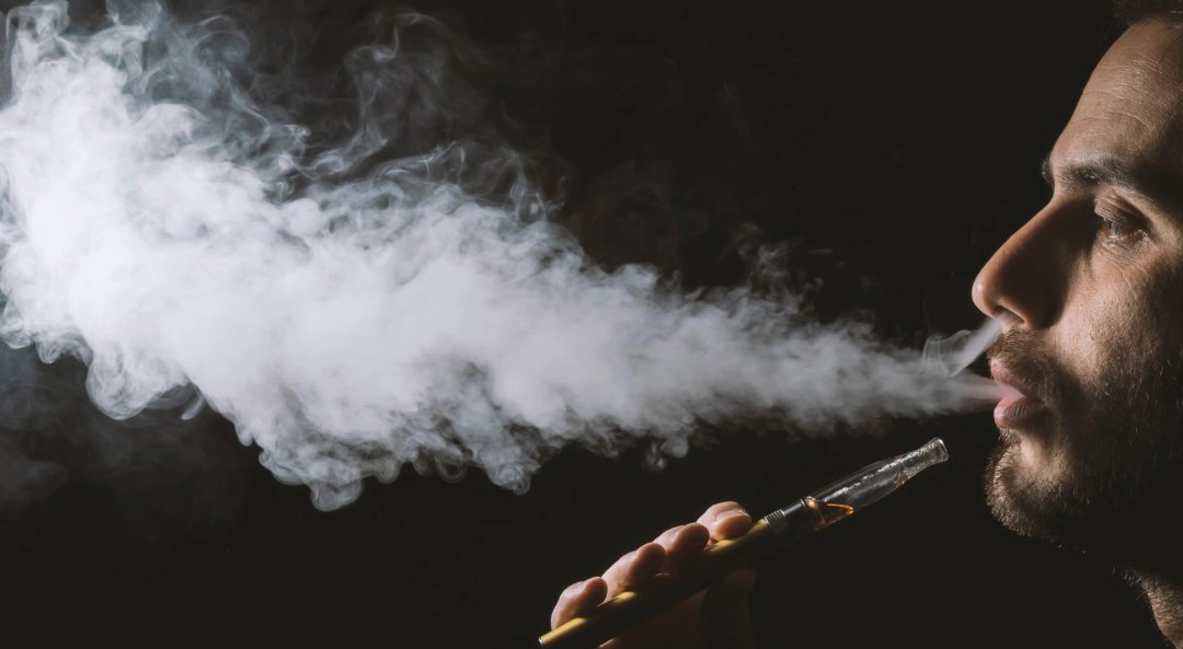 man vaping, exhaling a big cloud of smoke