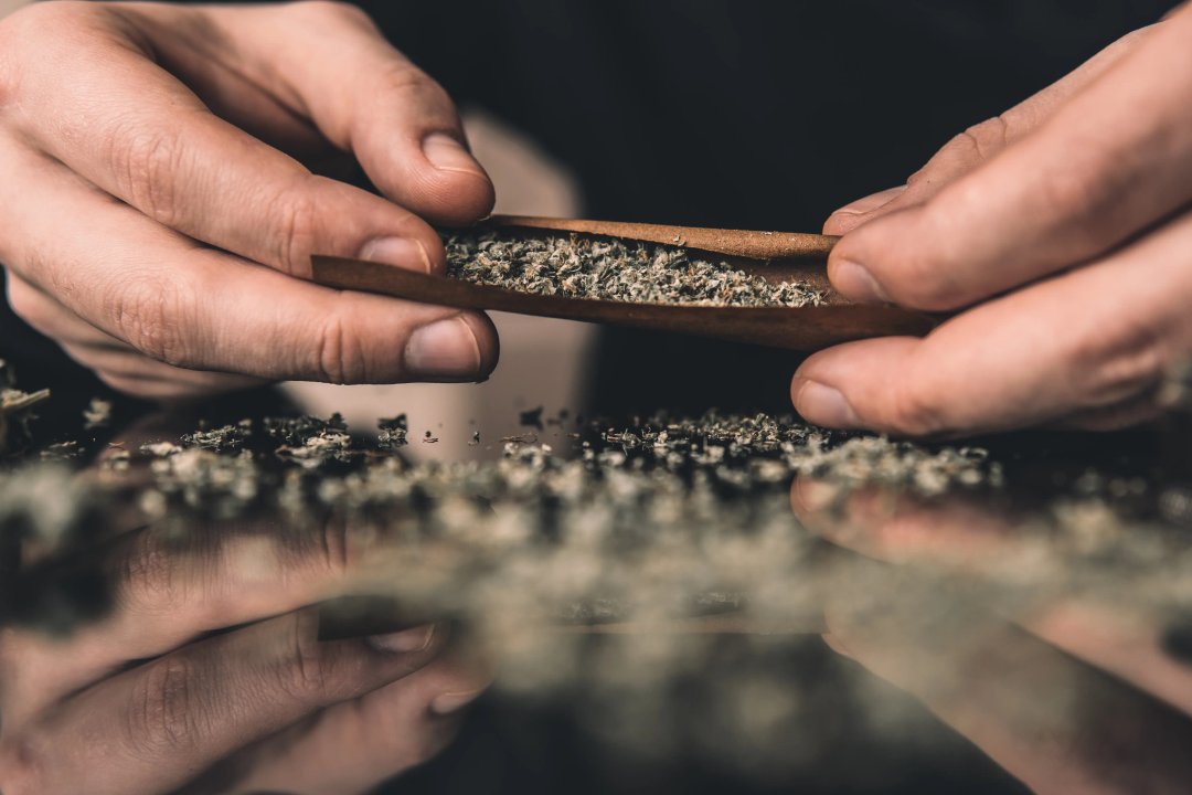 man filling a joint with flower