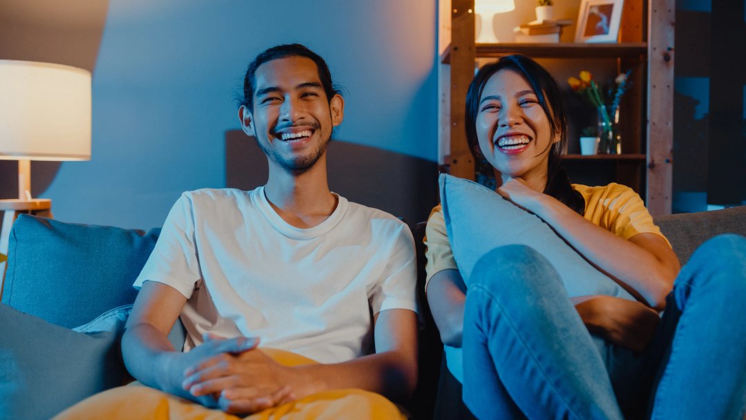 young couple laughing watching tv