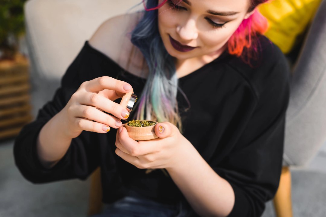 woman putting flower into a grinder