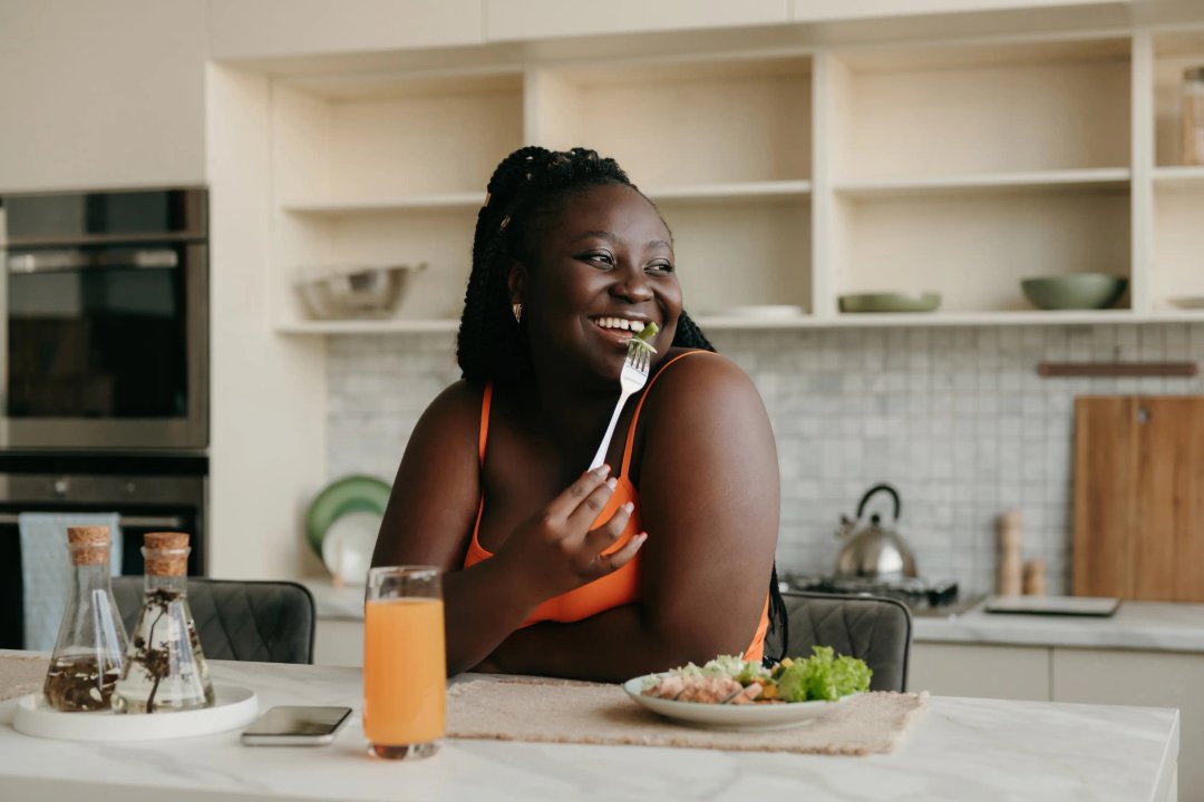 african american woman smiling whilst enjoying her healthy lunch