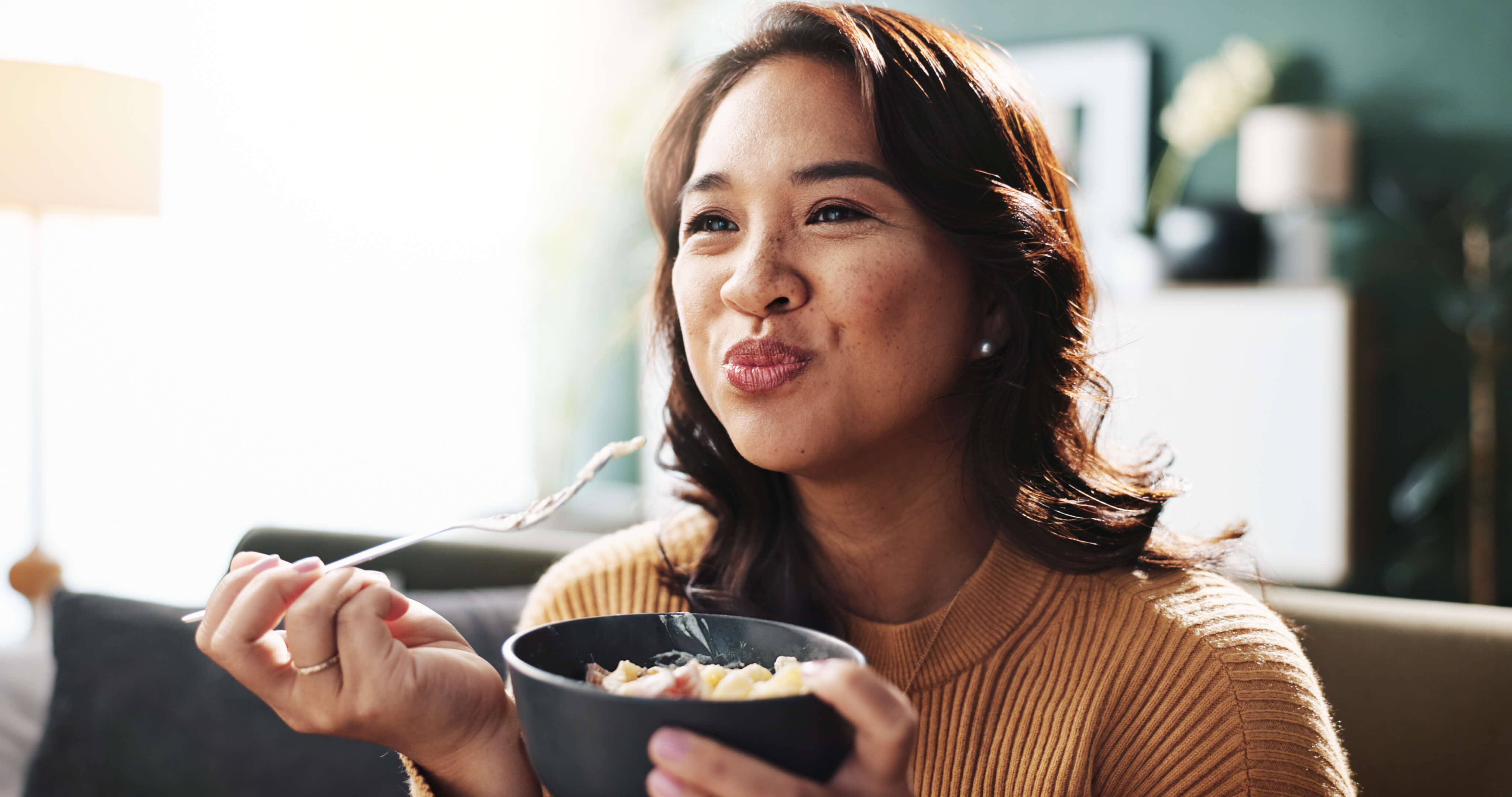 woman smiling as she enjoys her snack