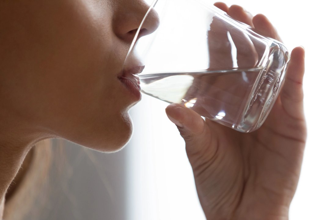 Closeup women face and hand holding glass of water