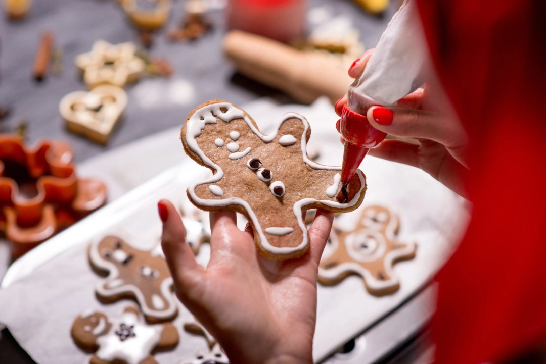 woman piping icing onto gingerbread men