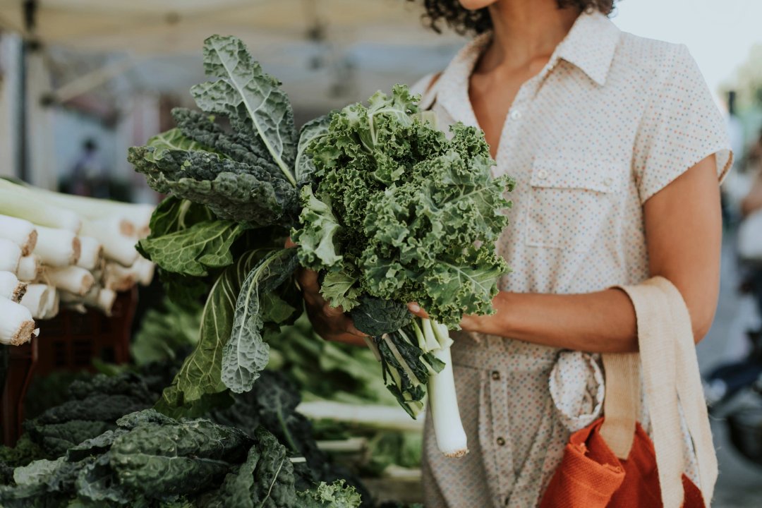 woman holding a bunch of kale at the farmer's market