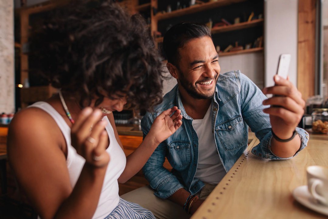 woman and man laughing at video on phone