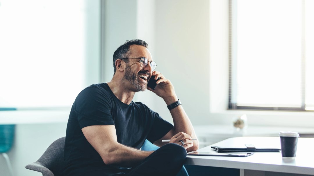 man laughing while taking a phone call