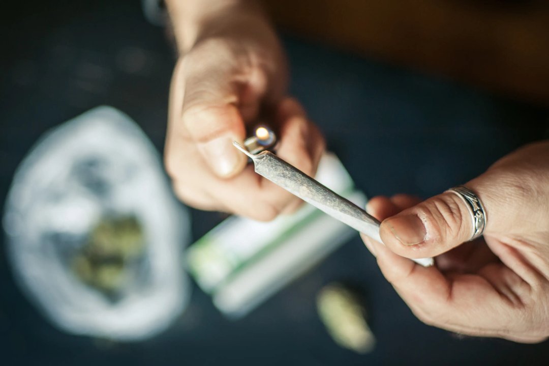 man lighting up a joint at the tip with a lighter