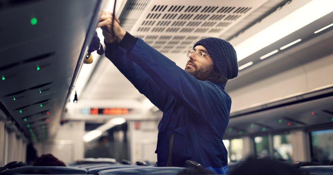 man putting luggage overhead on flight