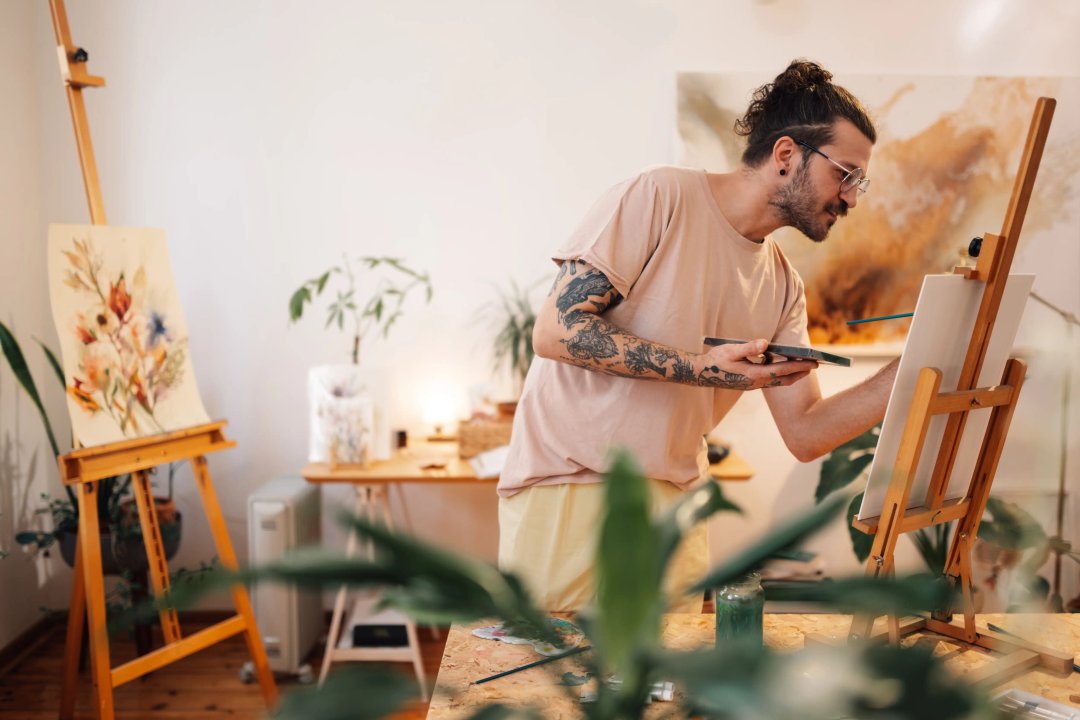 hippie man painting in a studio with plants