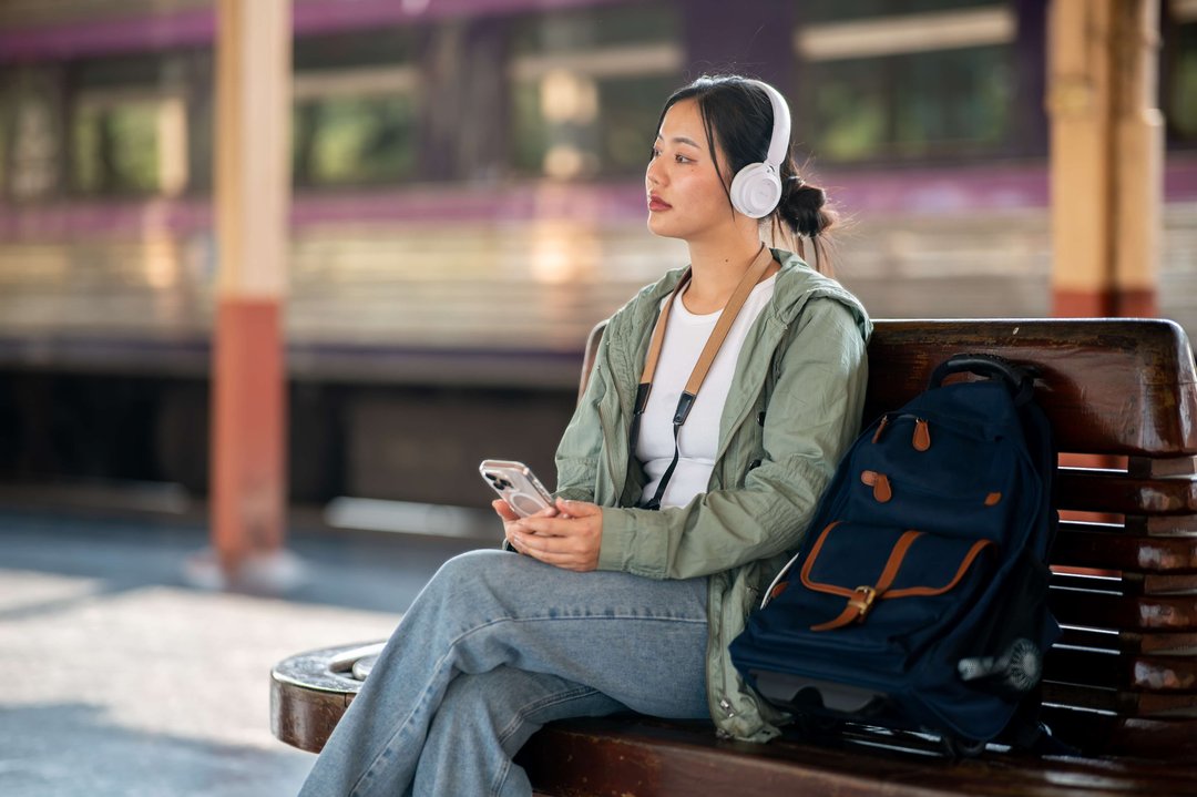 woman listening to music by the train