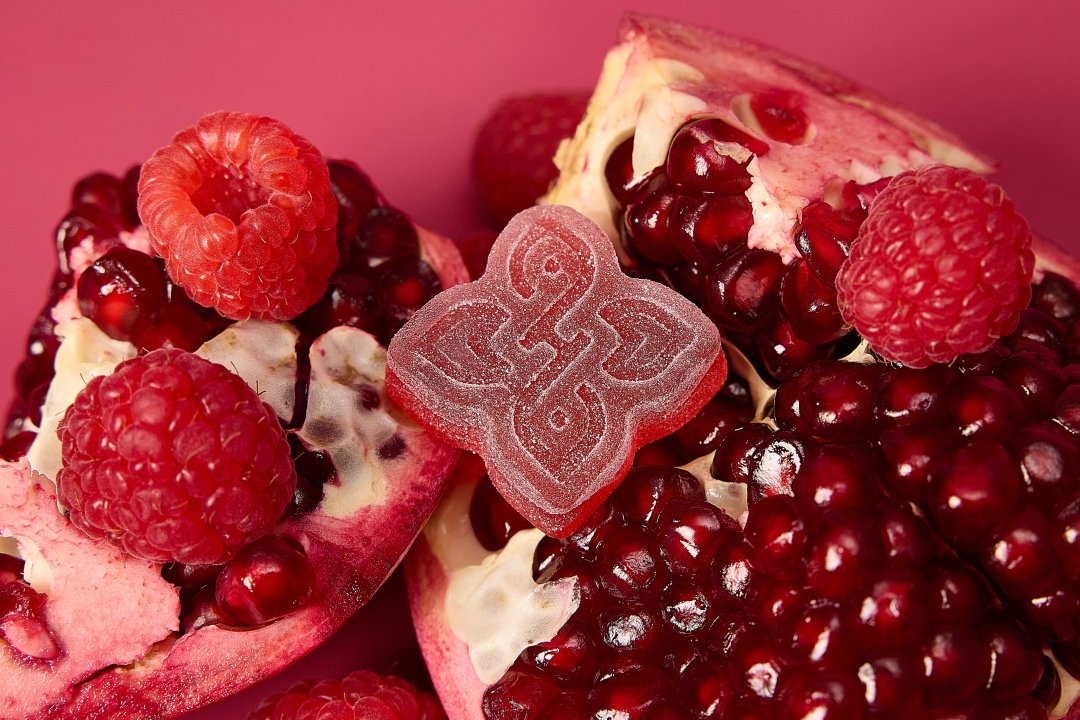 closeup of a red gummy on pomegranate and raspberry