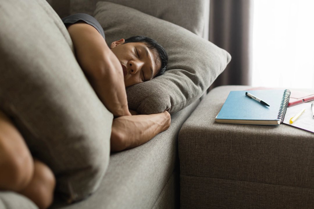 young asian man sleeping peacefully on his couch