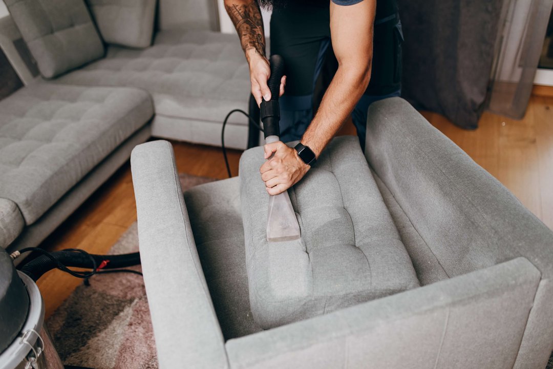 man steam cleaning the upholstery on his couch