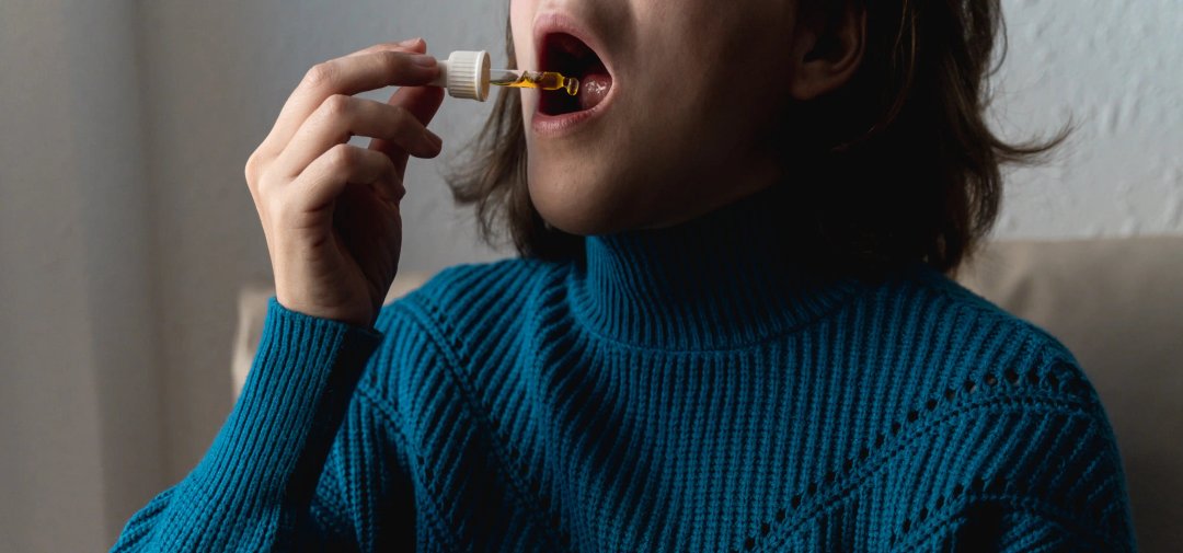 woman using a tincture oil dropper sublingually