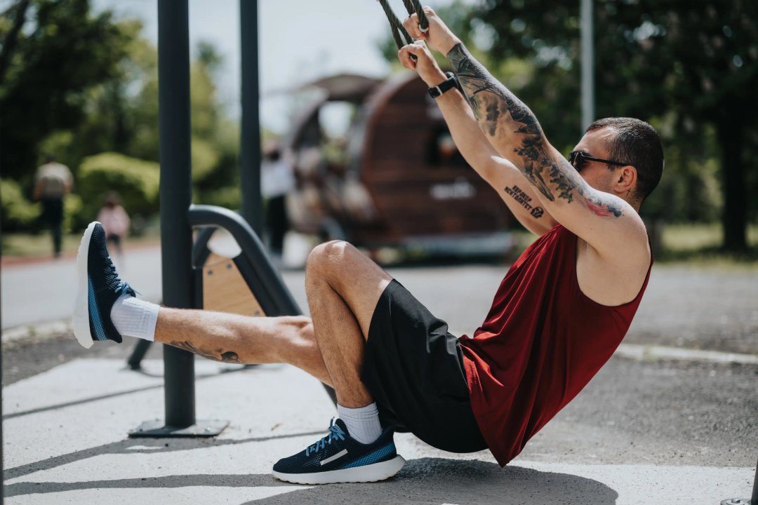 tattooed man performing a workout outside