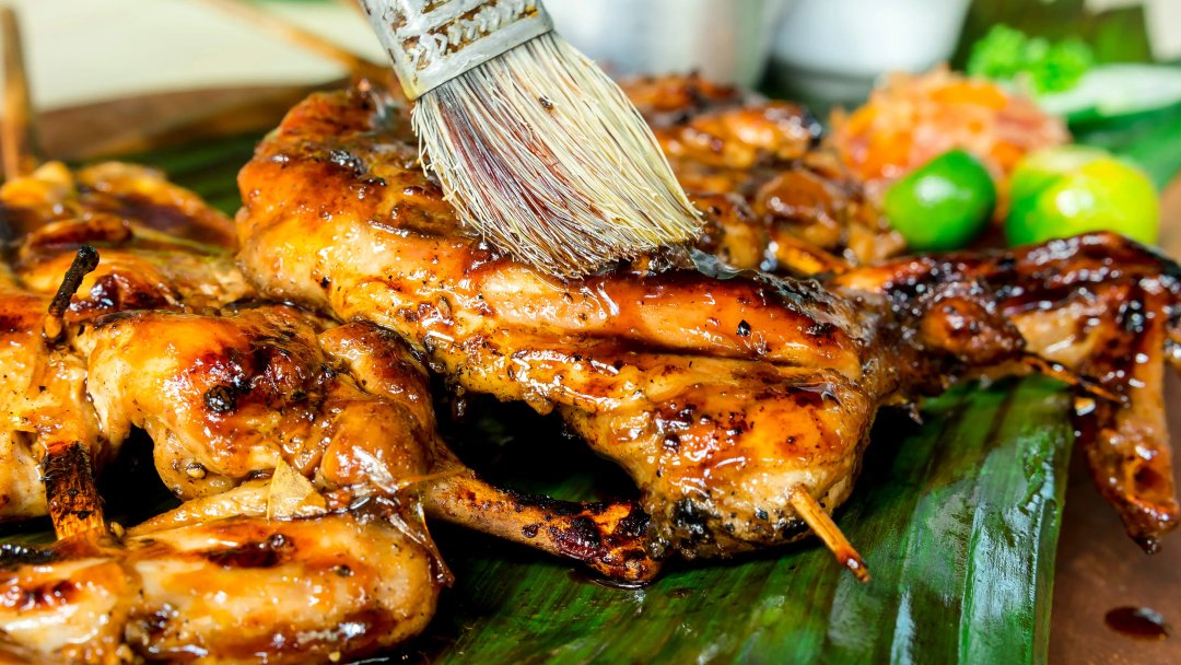 Applying marinade to juicy barbecued chicken with a brush.