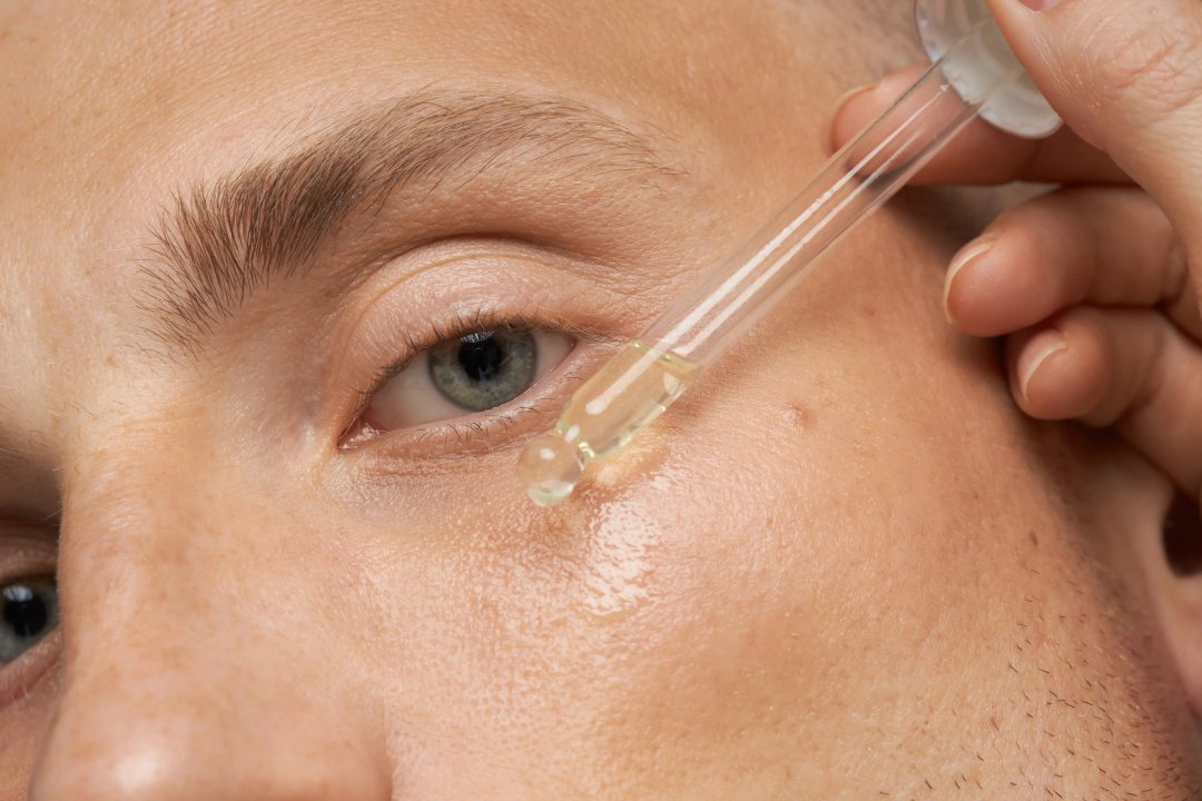 man applying tincture oil to her face