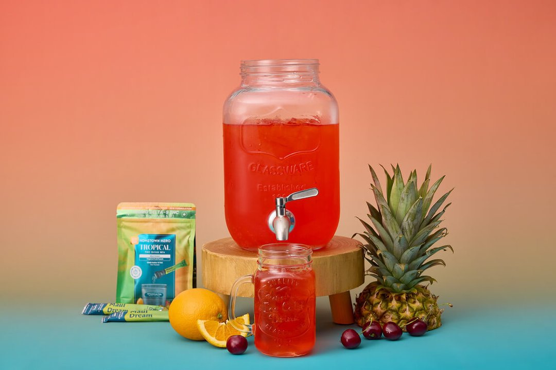 tropical thc drink mix on a table with glass of water to mix it into