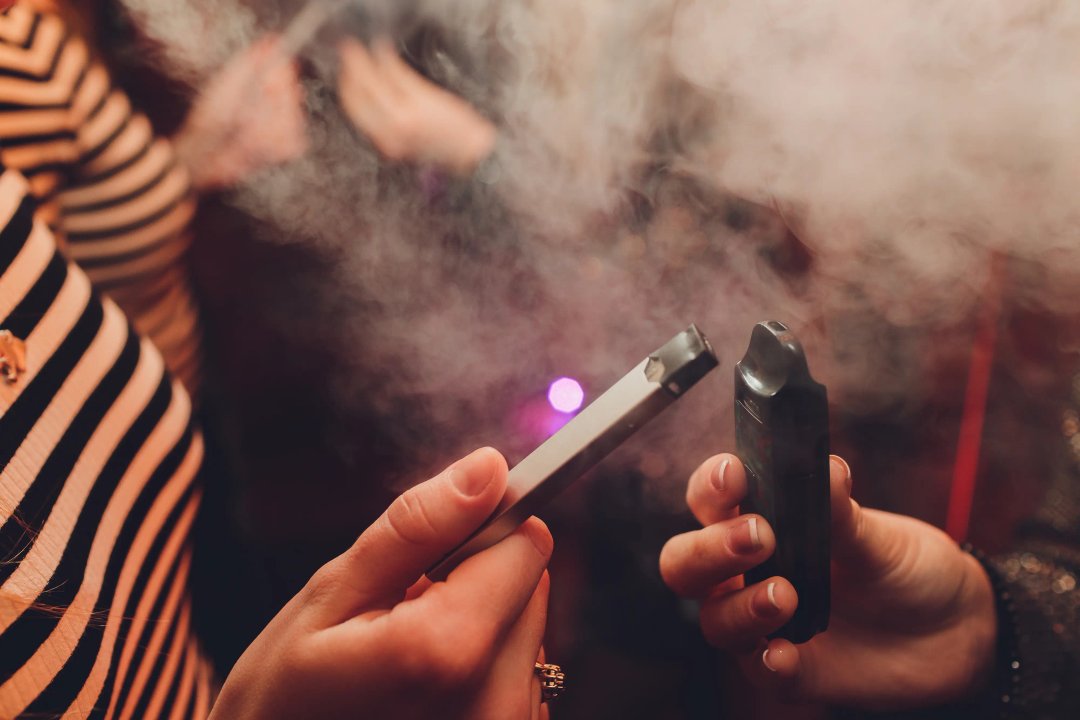 two young people holding vapes in their hands