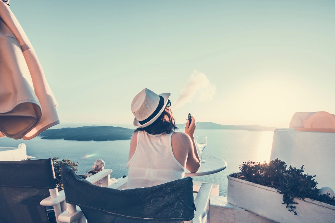 woman vaping in a beautiful summer vacation spot santorini beach