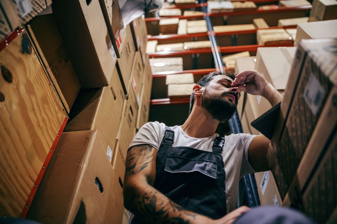 man stressed in a warehouse working